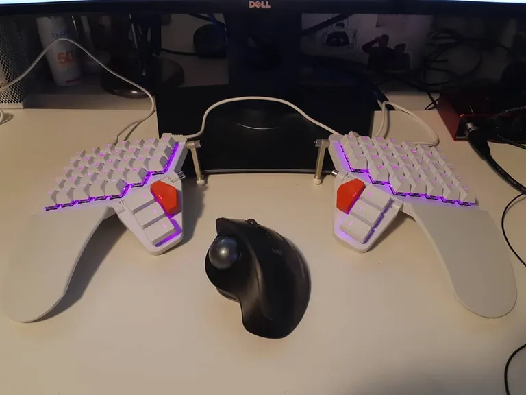 My white Moonlander with purple underglow and its wide palm rests, a trackball between the halves